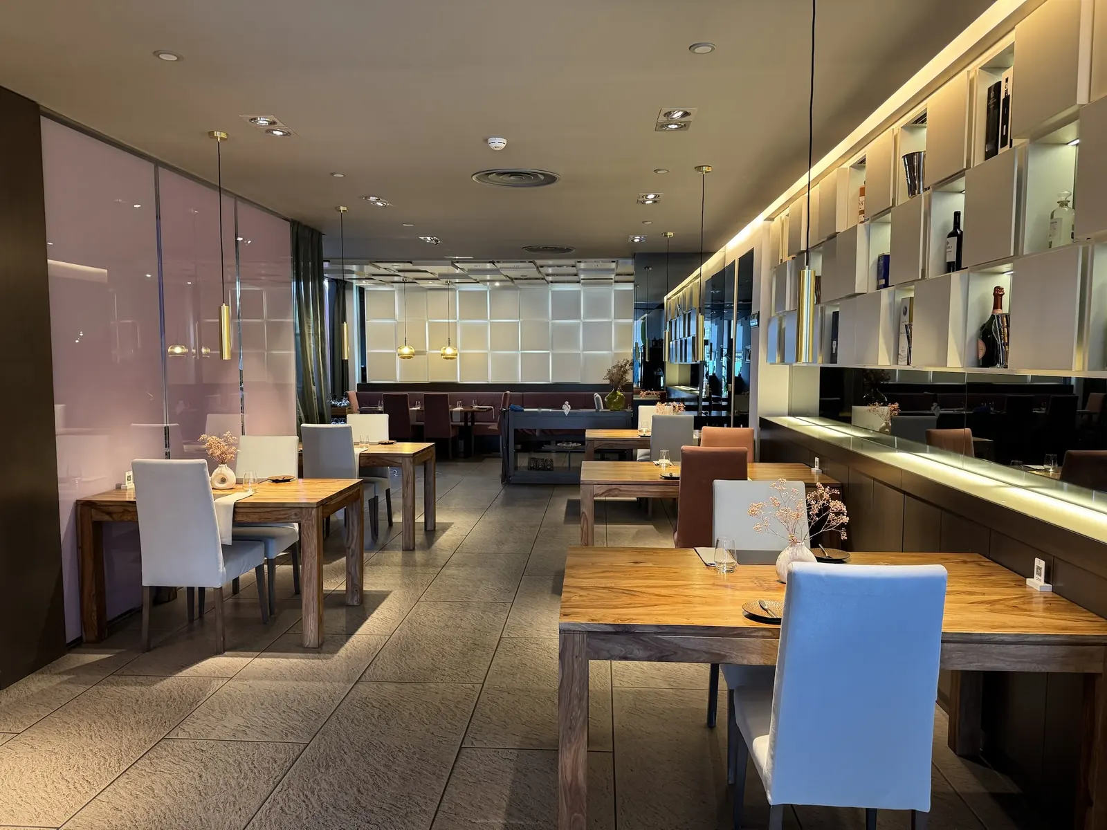 Sala principal de El Quinto Sabor con mesas de madera y estantería de botellas iluminada